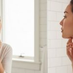 鏡で顎のラインを気にするストレートネックと二重あごに悩む女性の写真