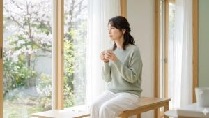 春バテで疲れを感じる40代女性が温かい飲み物で体を休める様子