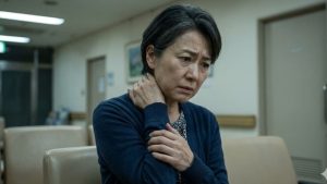 手術前の予期不安により首や肩がガチガチに緊張し、不安な表情で首を触る日本人女性のクローズアップ。患者の痛みに寄り添う。